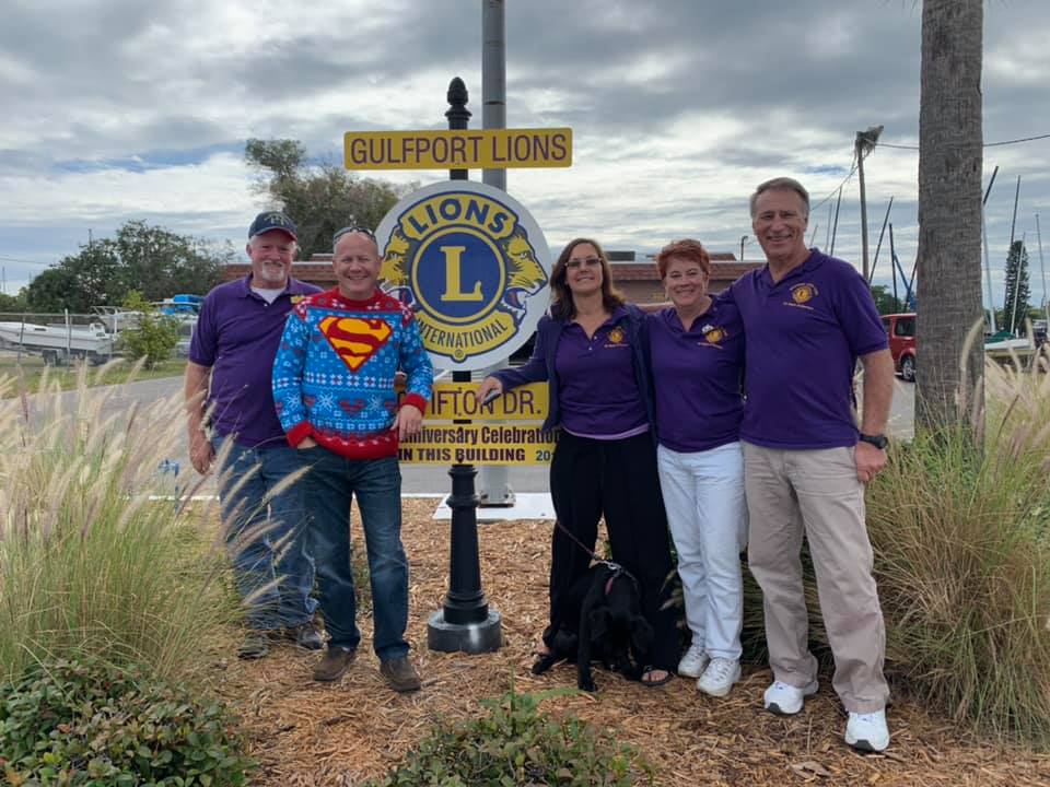 Five people in purple shirts pose by a 