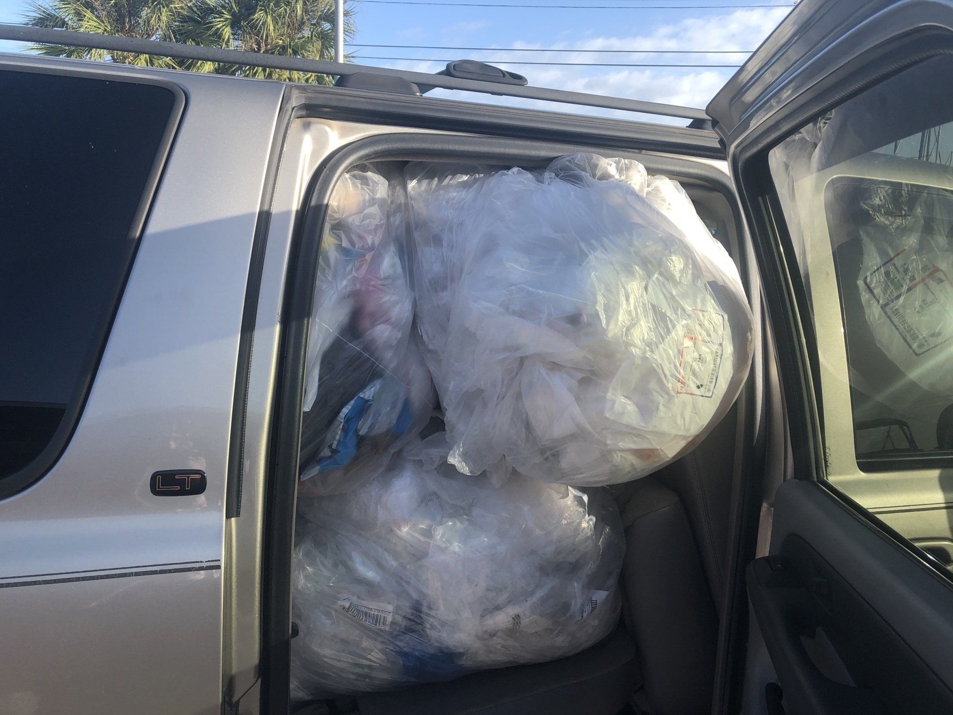 Silver SUV's open door revealing two large, clear plastic bags filled with unknown contents.