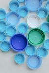 There are many different colored plastic bottle caps on the table.