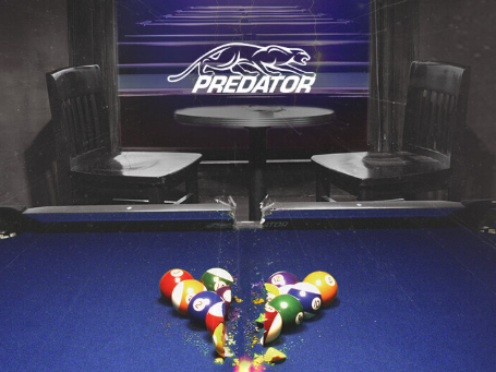 A woman in a red coat plays pool while a man watches with a pool cue in a dimly lit room.