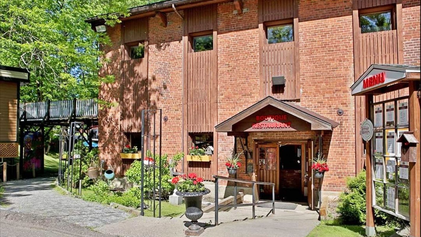 Un grand bâtiment en briques avec un porche en bois et une cabine téléphonique devant.