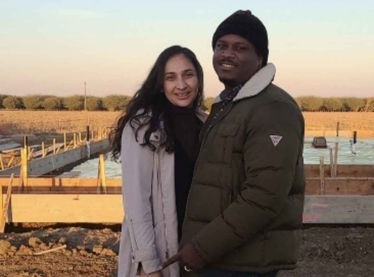 Woman with long, reddish-brown hair, freckles, and a subtle smile, wearing a blue sweater; indoors.