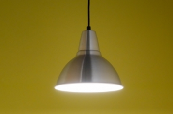 A pendant light is hanging from the ceiling in front of a yellow wall.