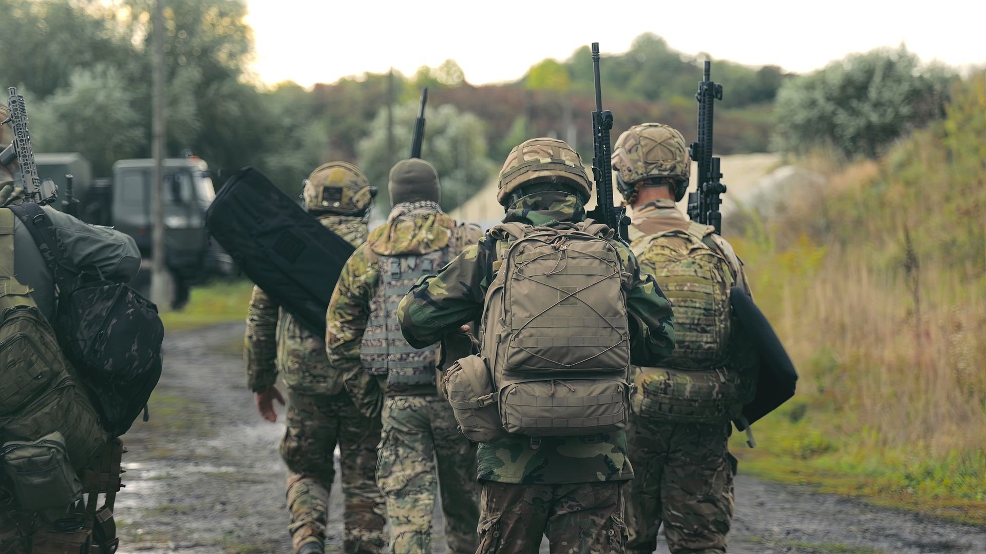 Soldier in camouflage with a German Shepherd dog overlooking a body of water. Sunny day.