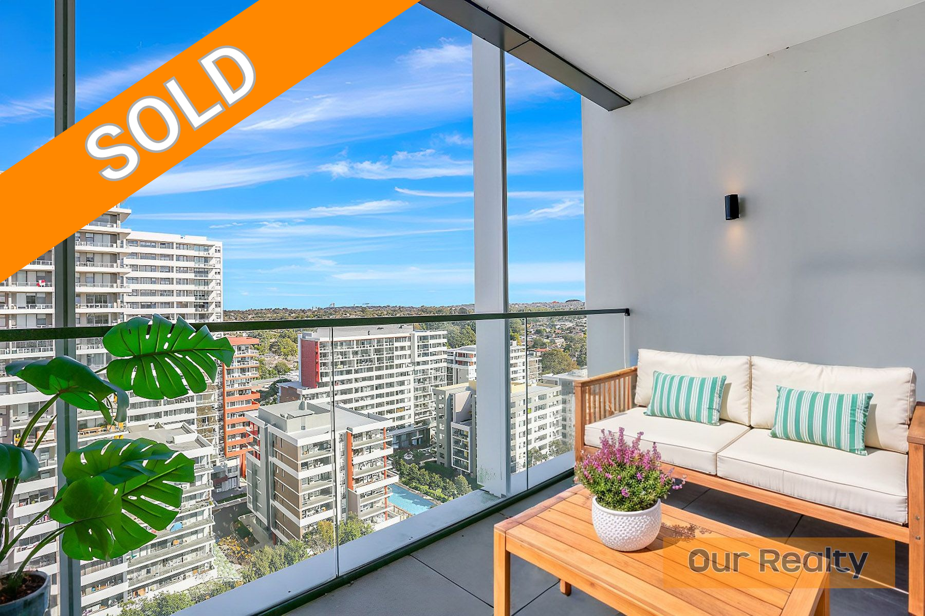 A balcony with a couch and a table with a view of a city.