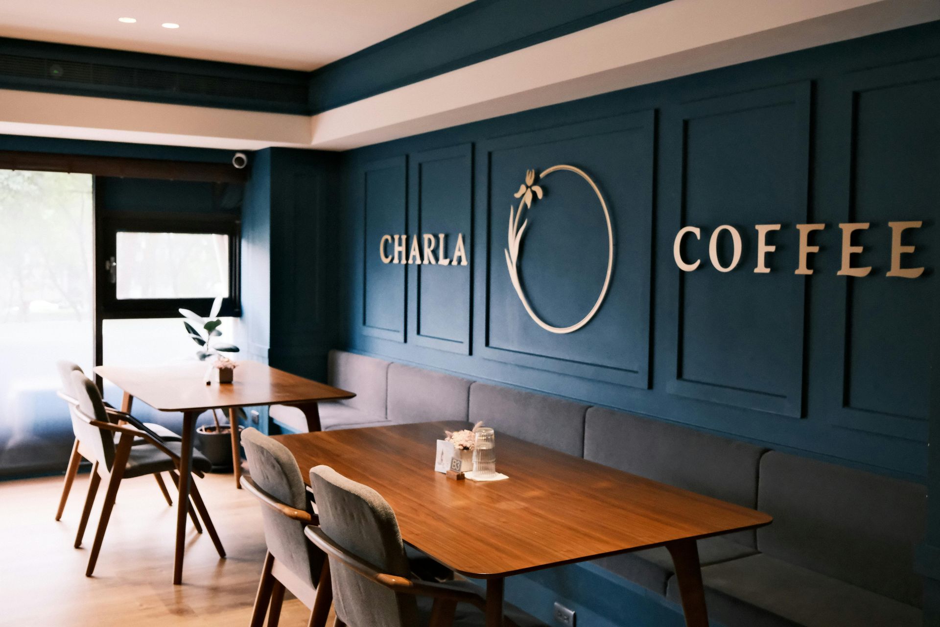 Interior of CHARLA COFFEE shop with teal walls, wooden tables, and gold lettering.