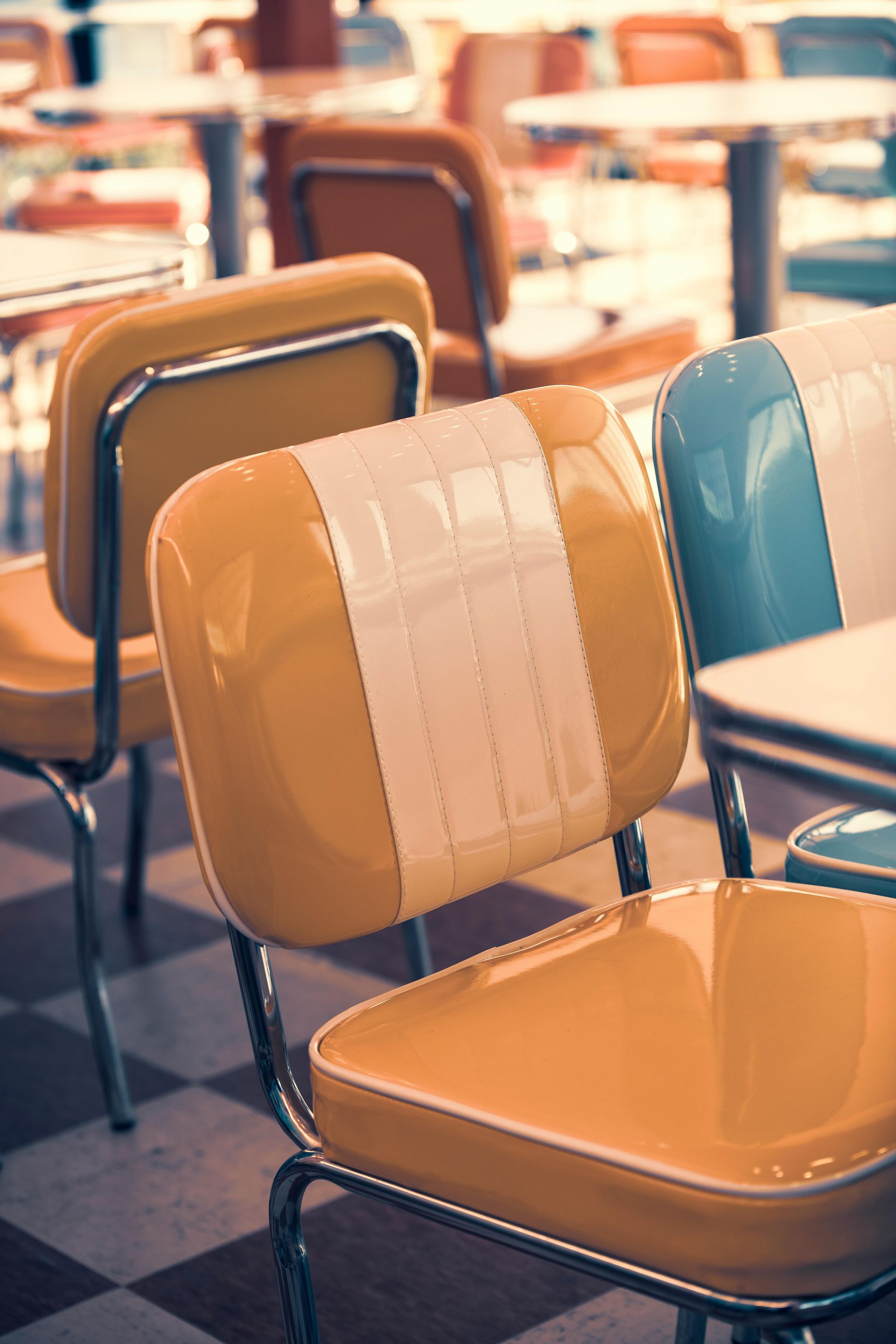 Retro diner chairs, yellow, blue, and white, sit near checkered floor.
