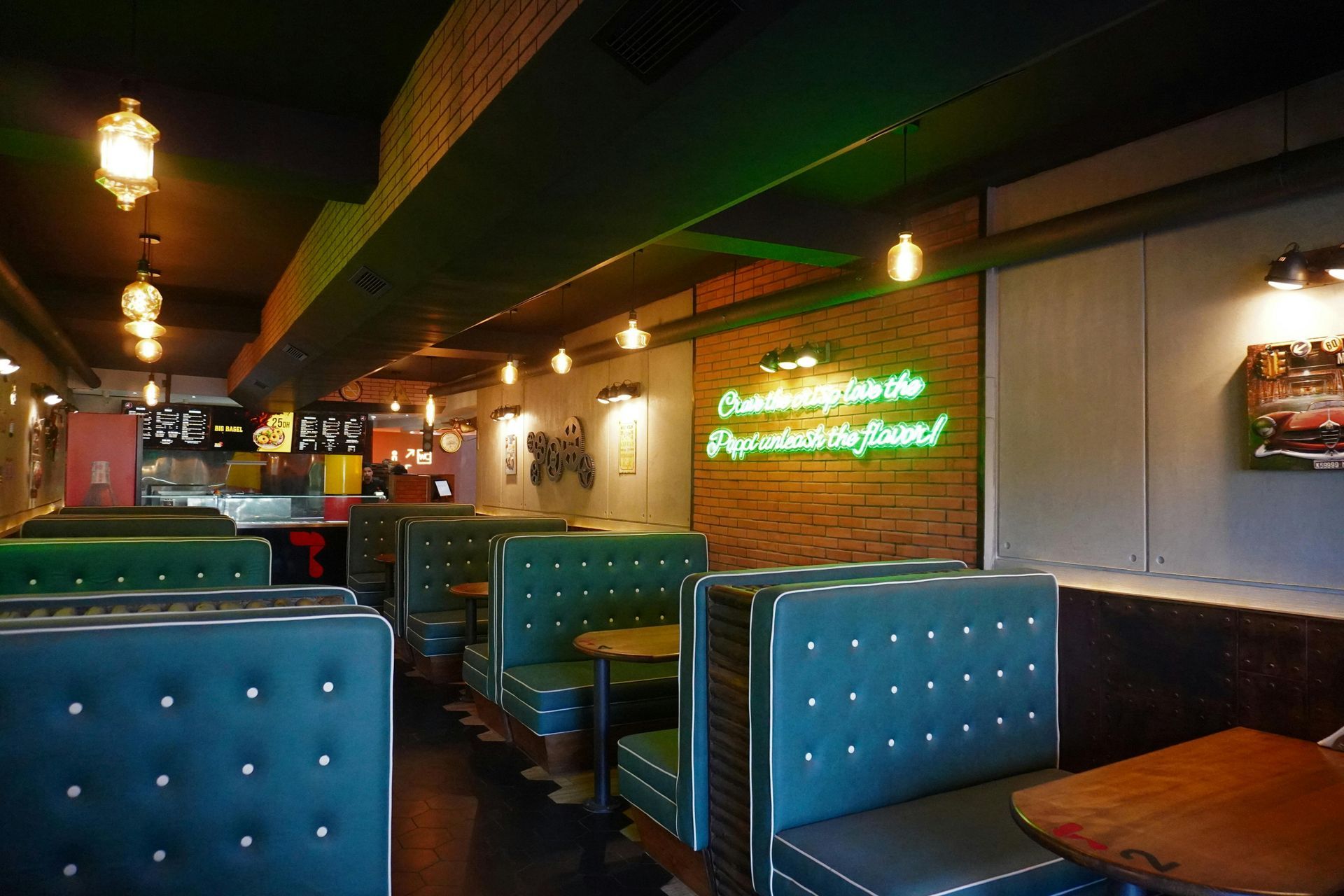 Inside a retro restaurant: teal booths, neon sign, brick wall, vintage decor.