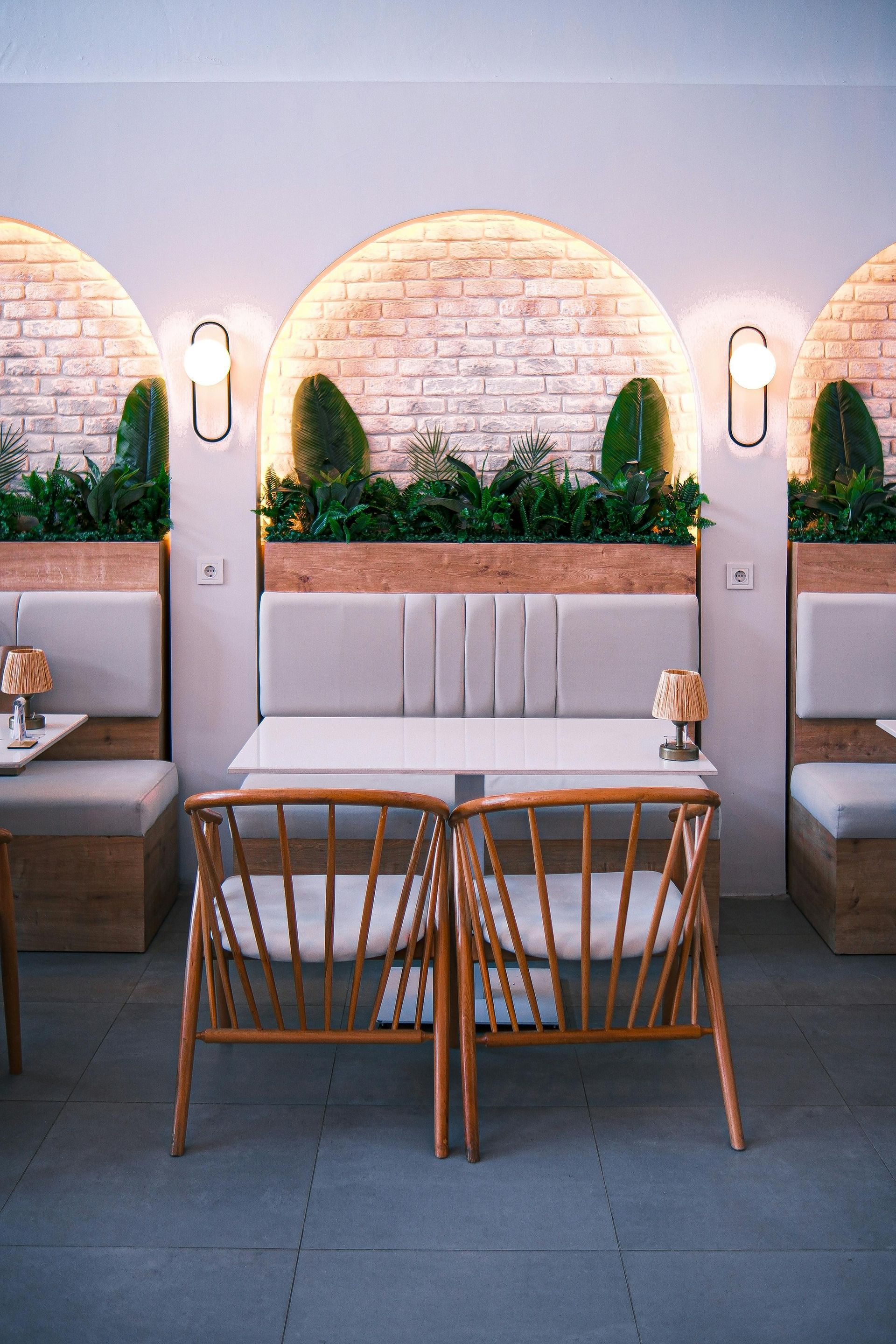 Restaurant interior with arched brick accents, cushioned booths, wooden tables, and chairs.