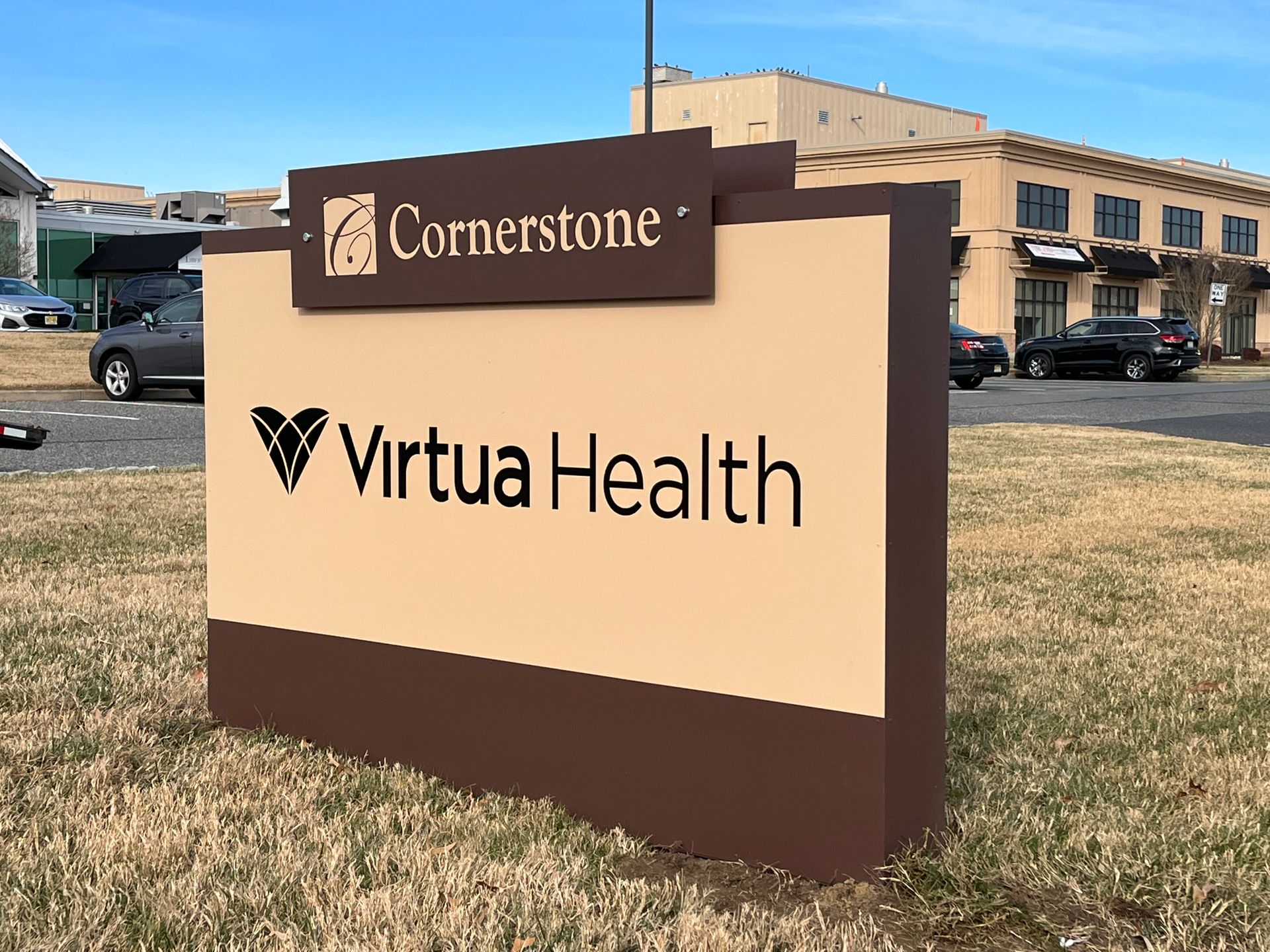 Sign for Virtua Health at Cornerstone, brown and beige with logo, near building and cars.