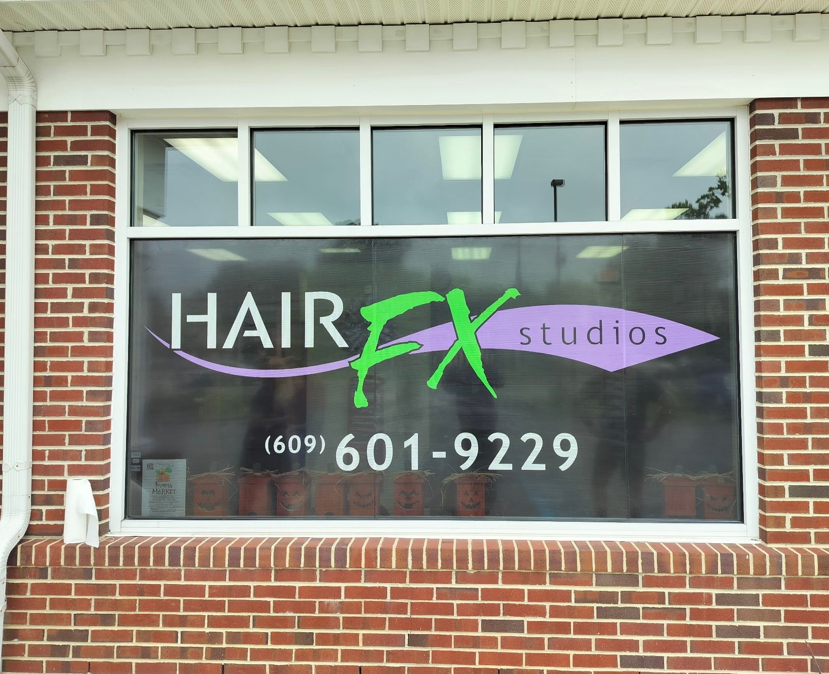 Hair FX studios sign in a window with a phone number on a brick building.