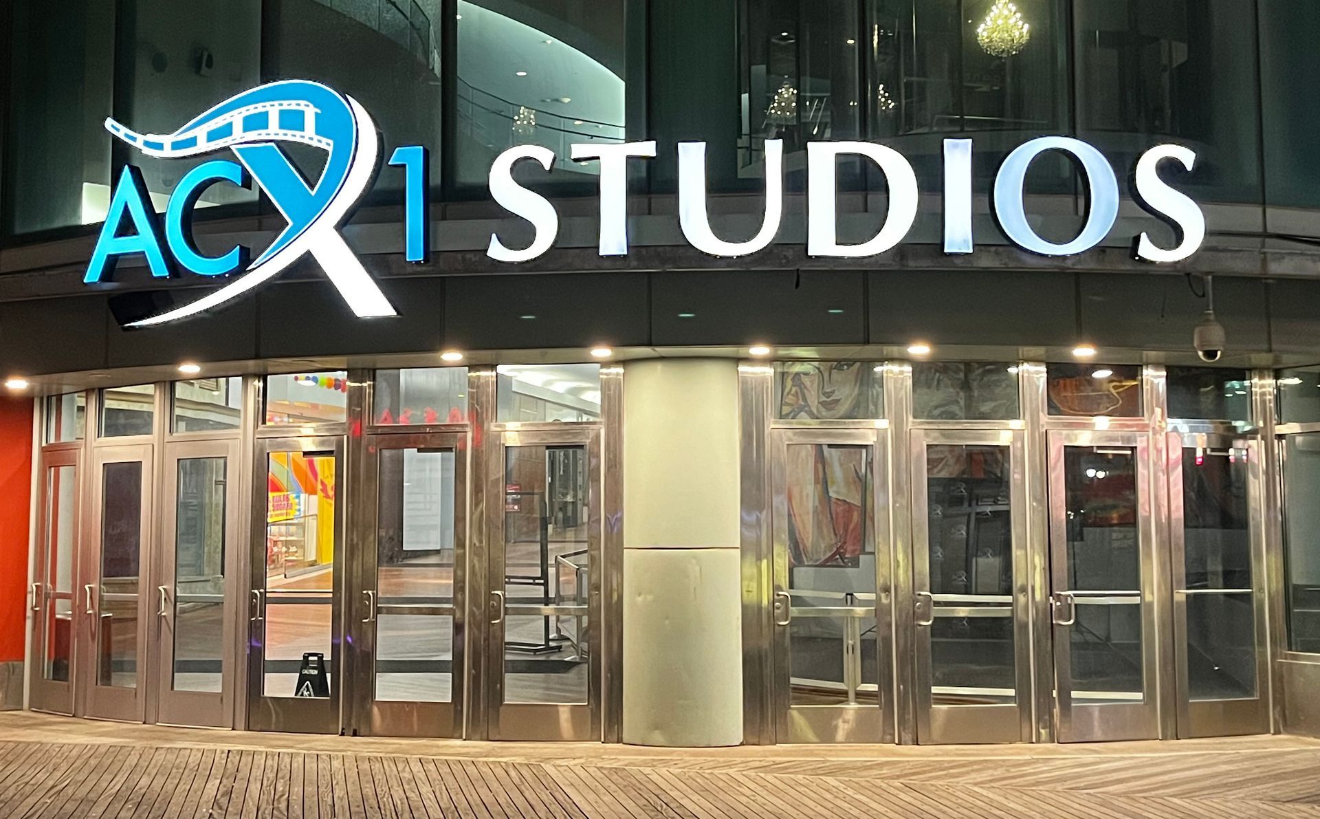 ACX1 Studios entrance with multiple glass doors and sign, lit at night.