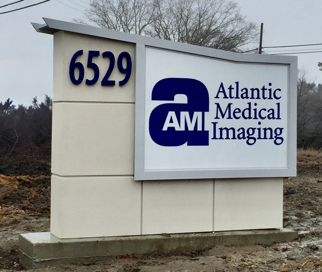 Sign for Atlantic Medical Imaging at 6529, with blue and white logo on light-colored building.