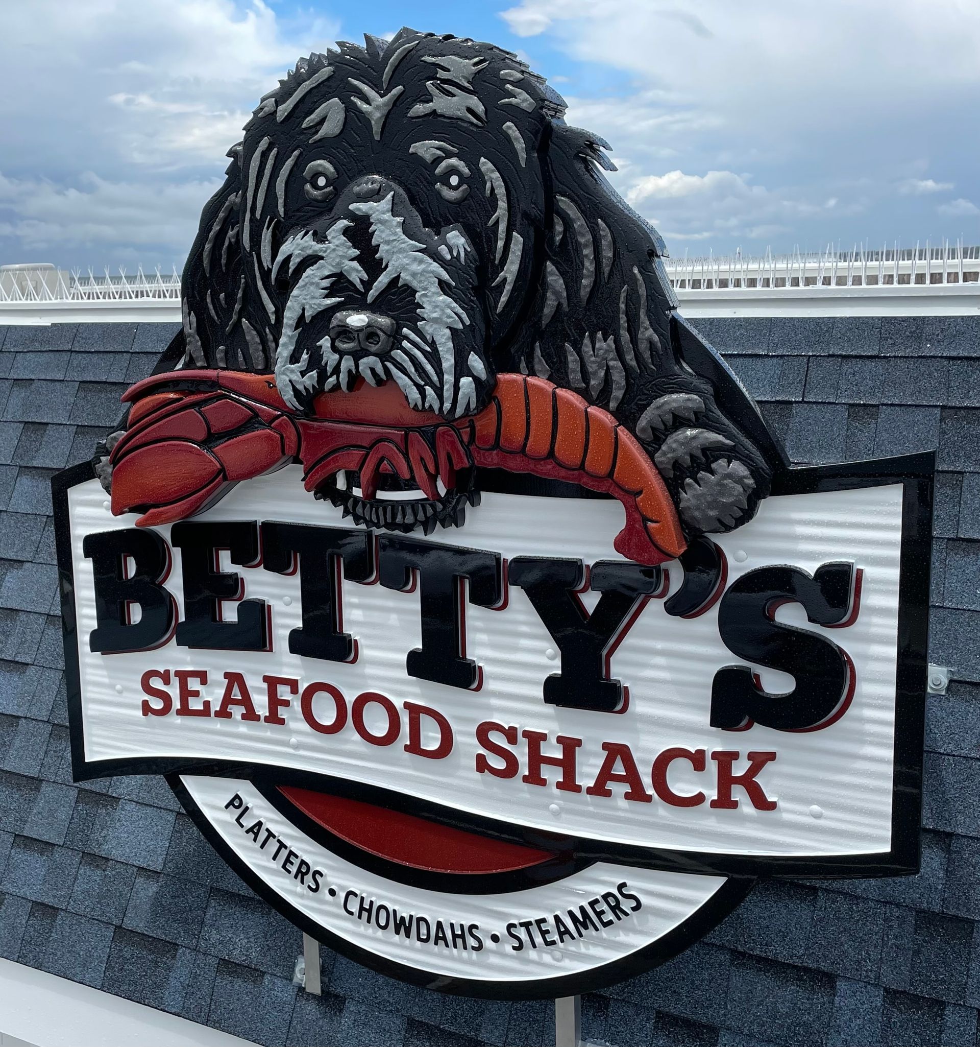 Sign for Betty's Seafood Shack: dog holding a lobster above the restaurant's name.