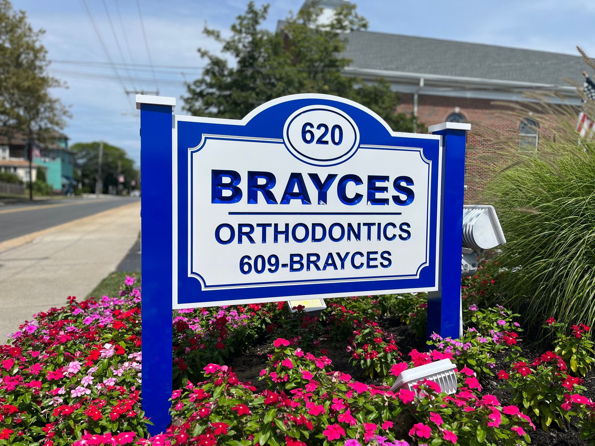 Sign for Brayces Orthodontics: blue and white sign, address 620, flowers in front.