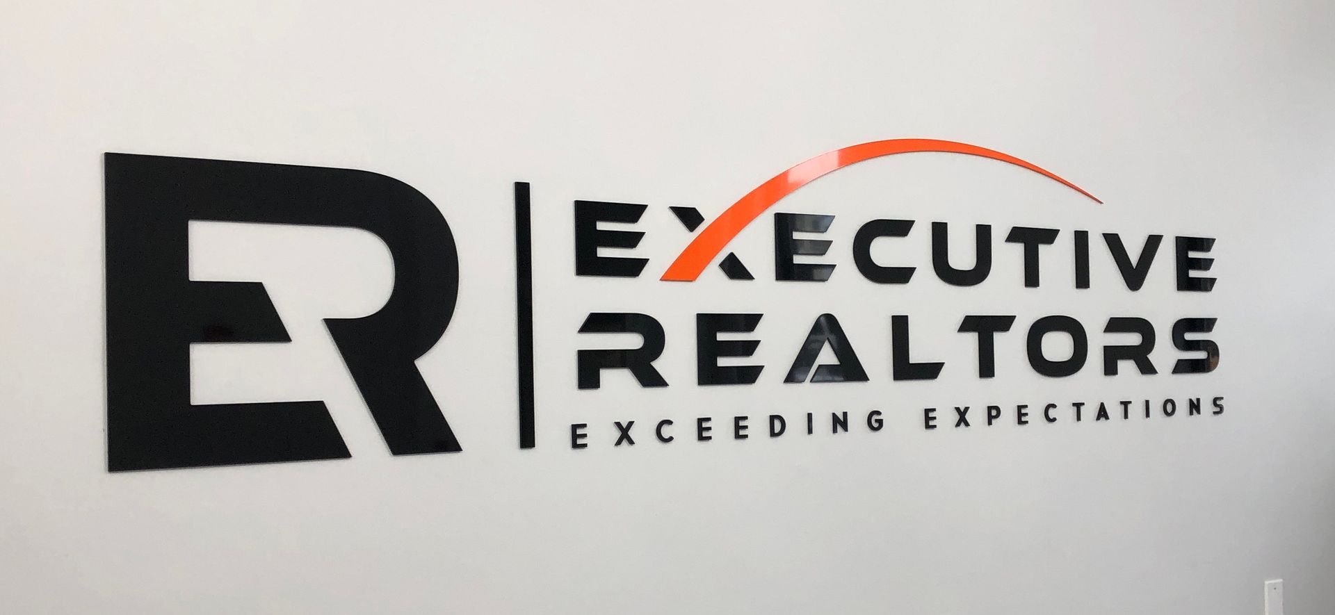 Executive Realtors logo on a white wall. 