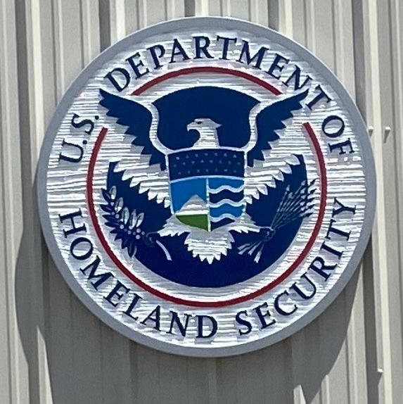 U.S. Department of Homeland Security emblem: a circular sign with an eagle, shield, and text on a building.