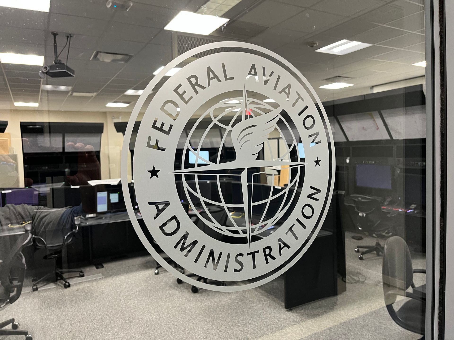 Federal Aviation Administration logo on a glass door, with control room visible behind.