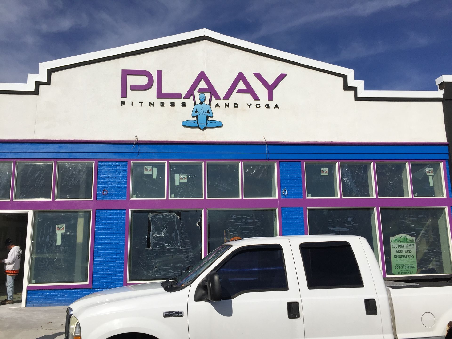 Plaay Fitness and Yoga sign above a blue and purple storefront, a white truck in front.