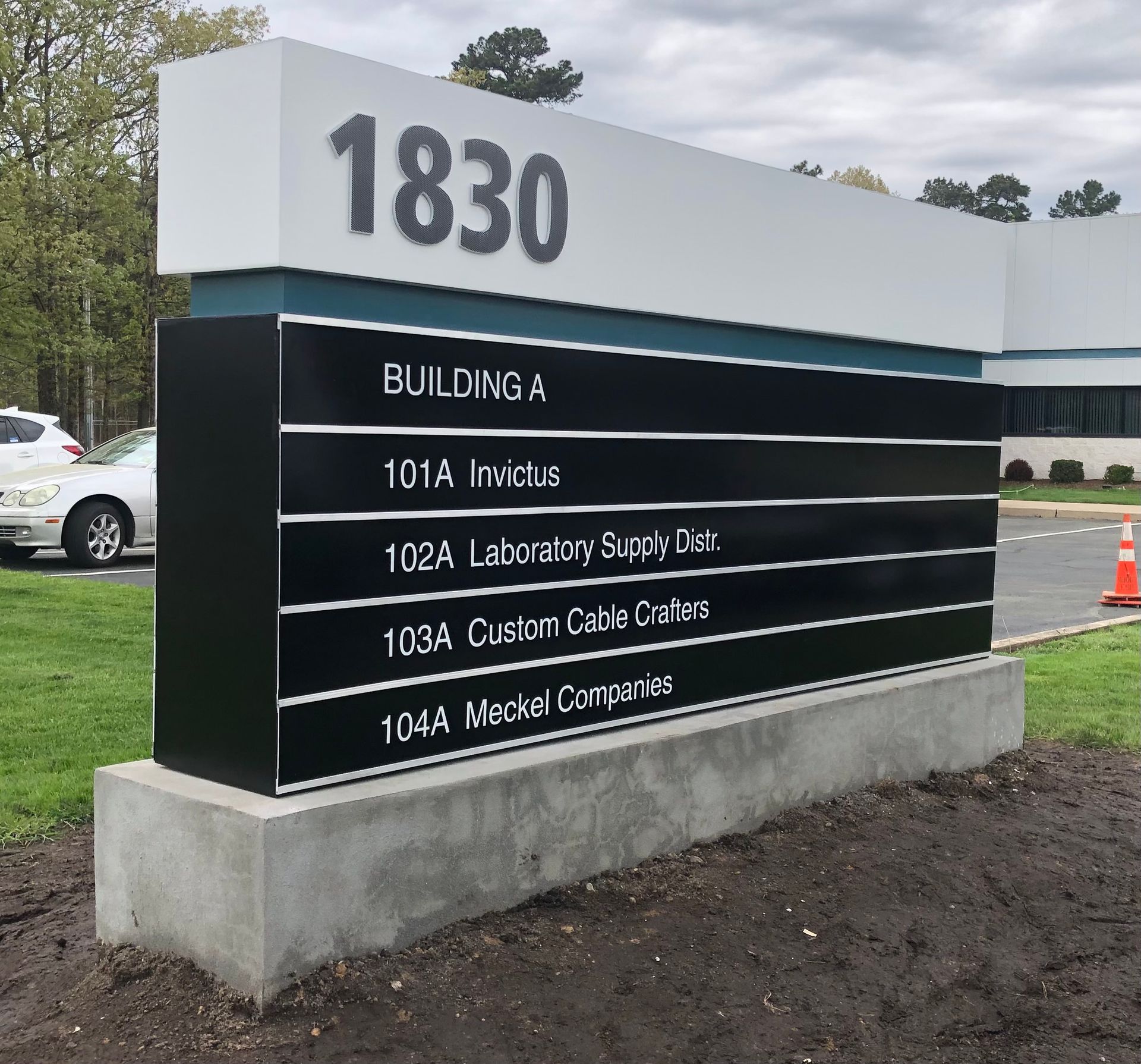 Sign at 1830, listing building A's businesses: Invictus, Laboratory Supply Dist., Custom Cable, and Mek Companies.