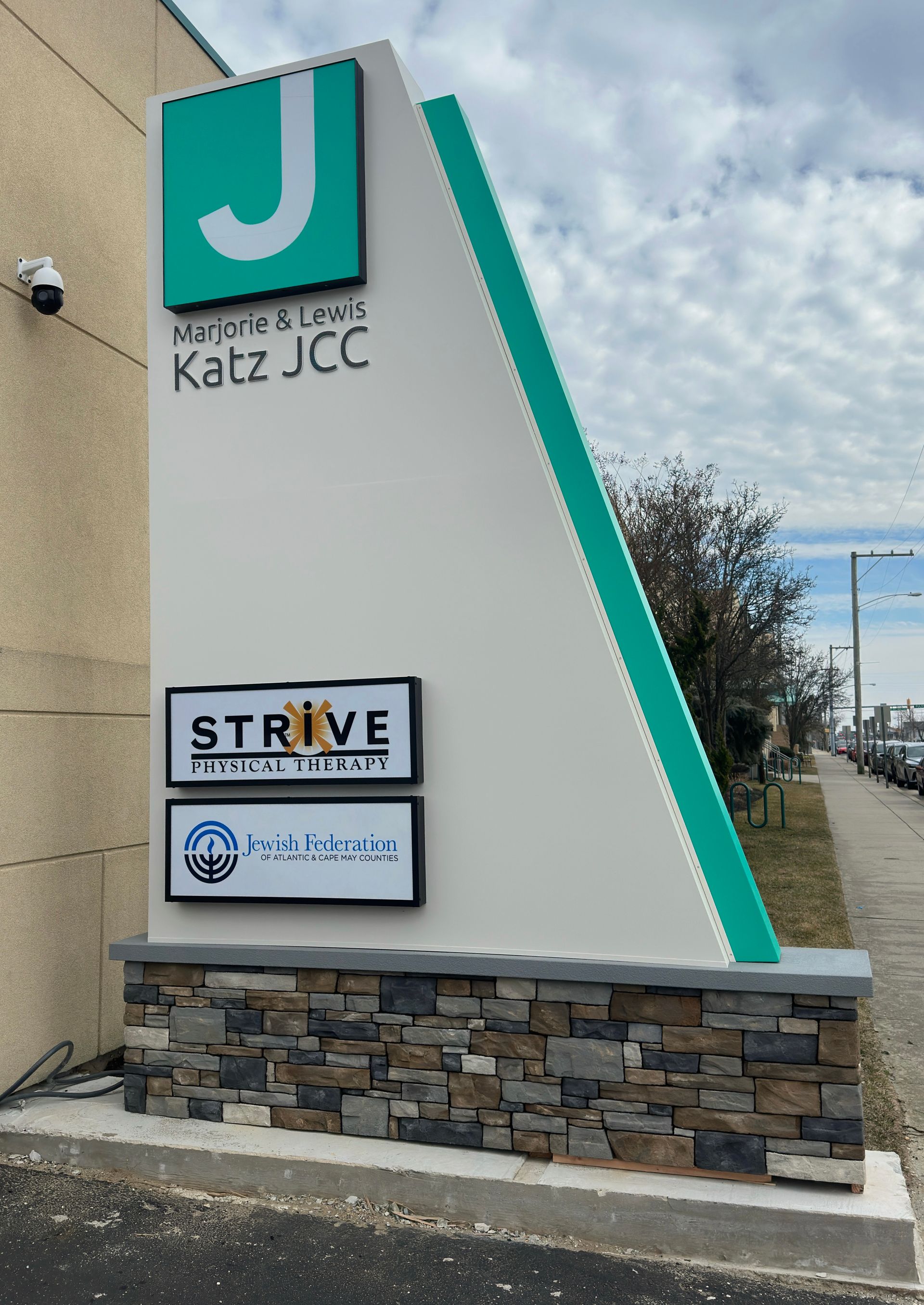 Sign for Katz JCC with green and white elements, and logos for 