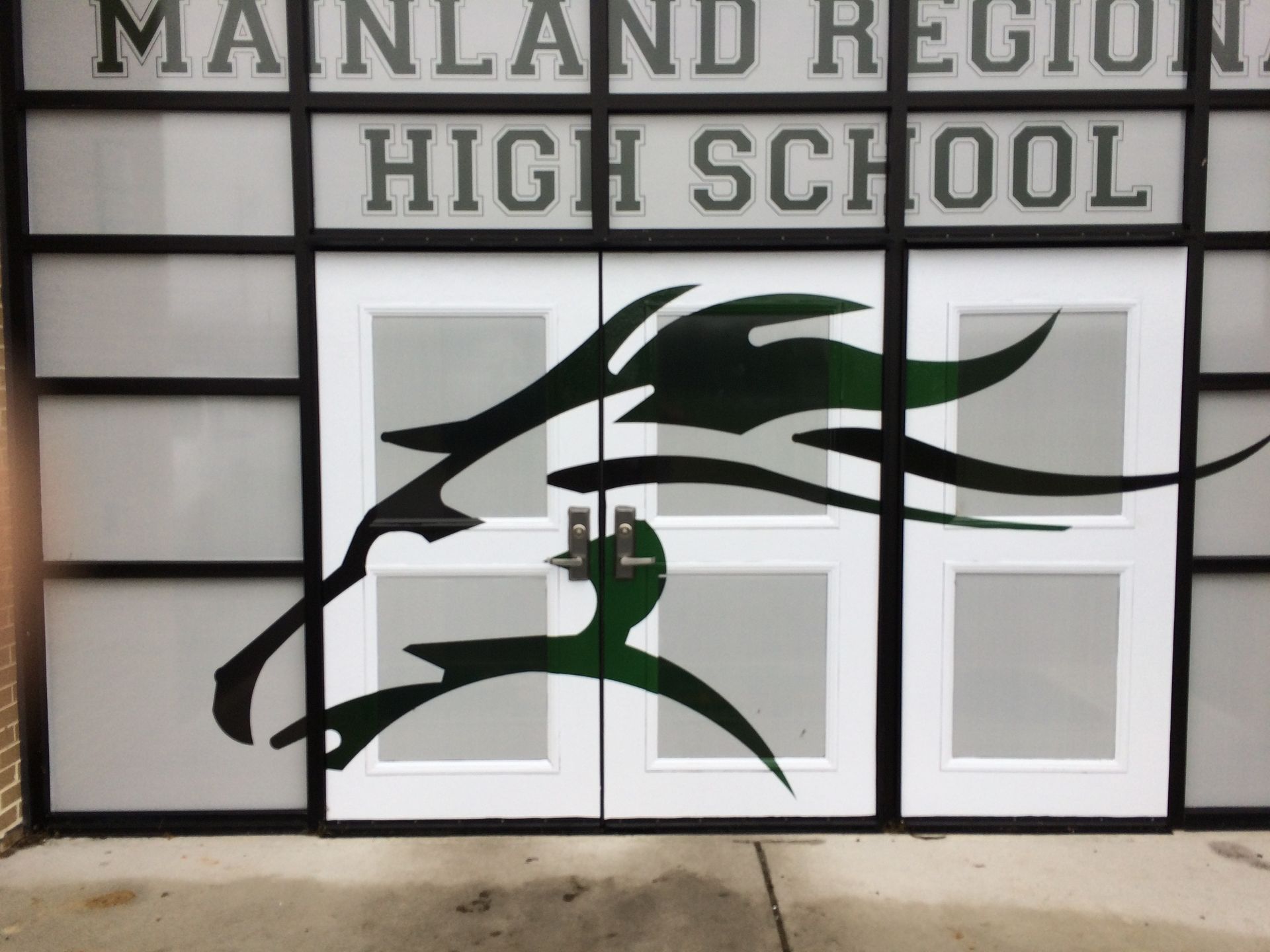 Mainland Regional High School doors with green and black cougar logo.