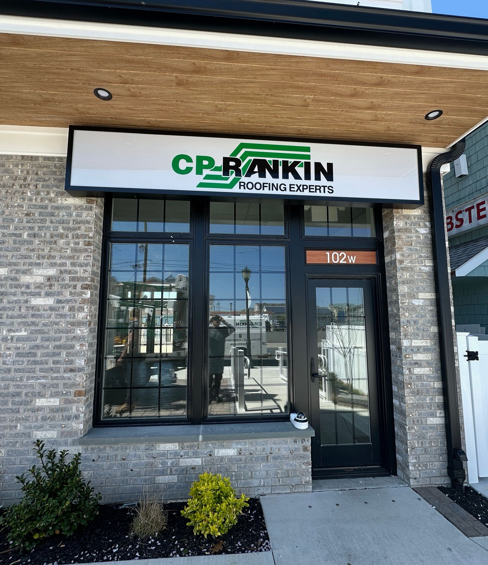 Sign for Sails Restaurant/Bar, with overlapping sail graphic, black background, silver lettering on gray stone base.