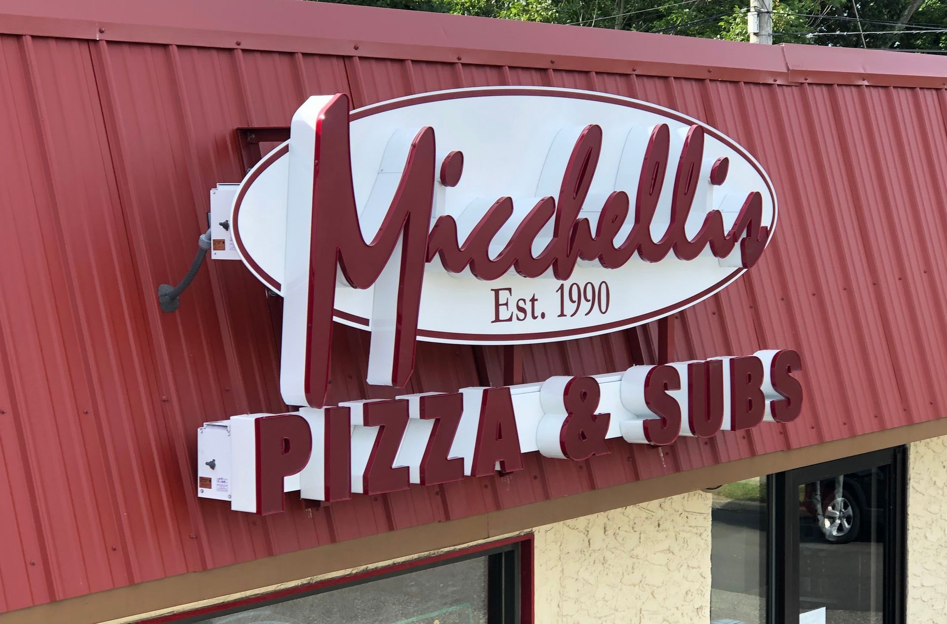 Sign for Michelli's Pizza & Subs, red roof. Oval sign: 