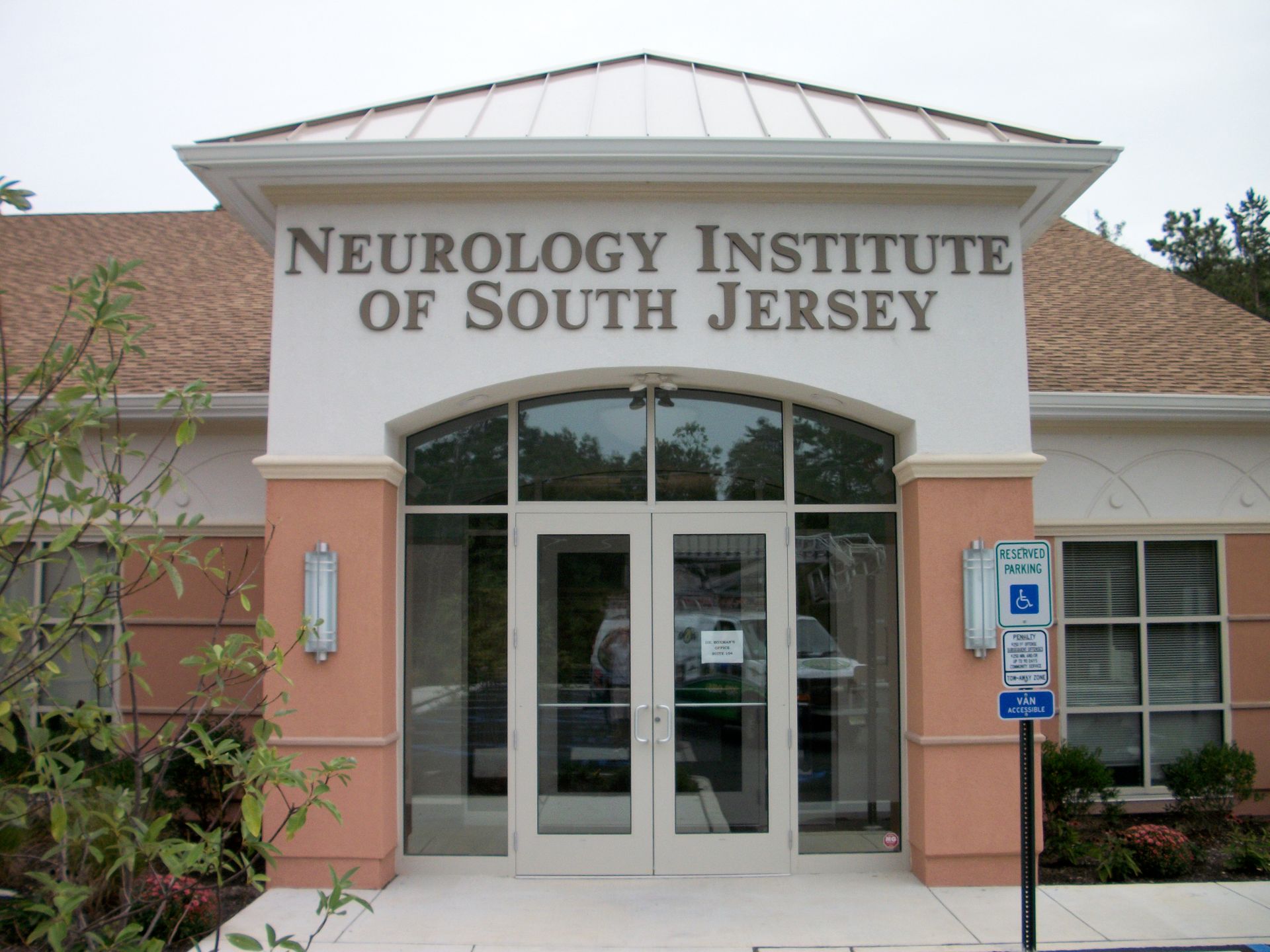 Neurology Institute of South Jersey building with a glass entrance, brown roof, and pink accents.