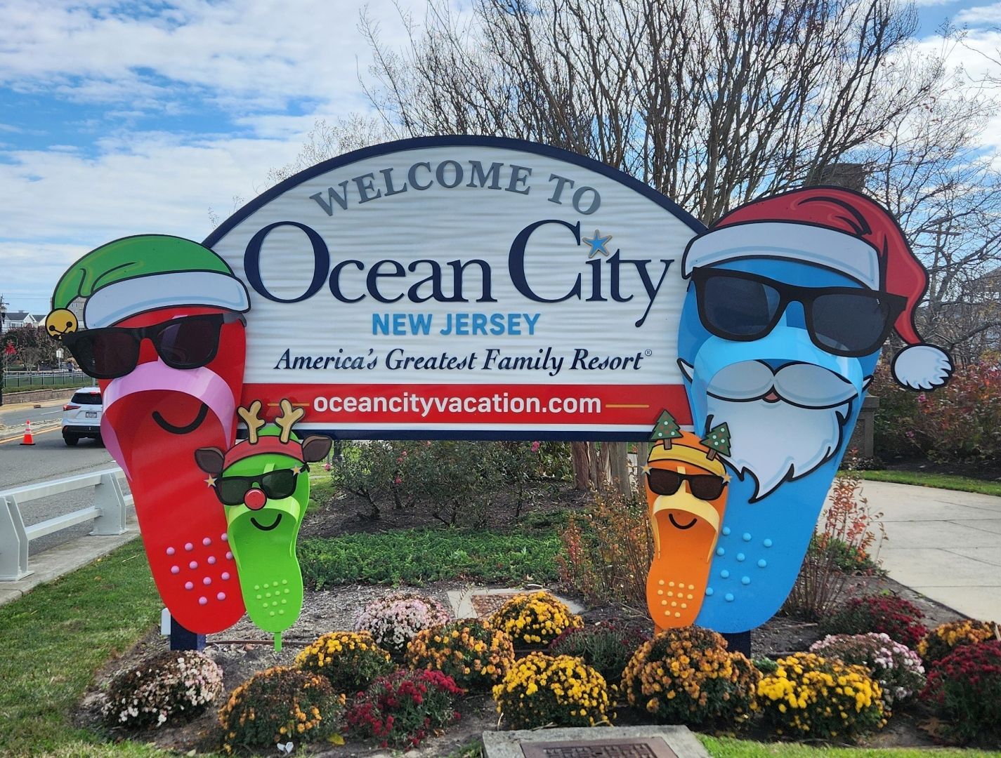 Ocean City, New Jersey welcome sign with Santa-themed pickle decorations wearing sunglasses.