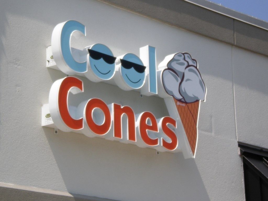 Cresson Hill sign, green background with gold text and sunrise graphic, on stone base.