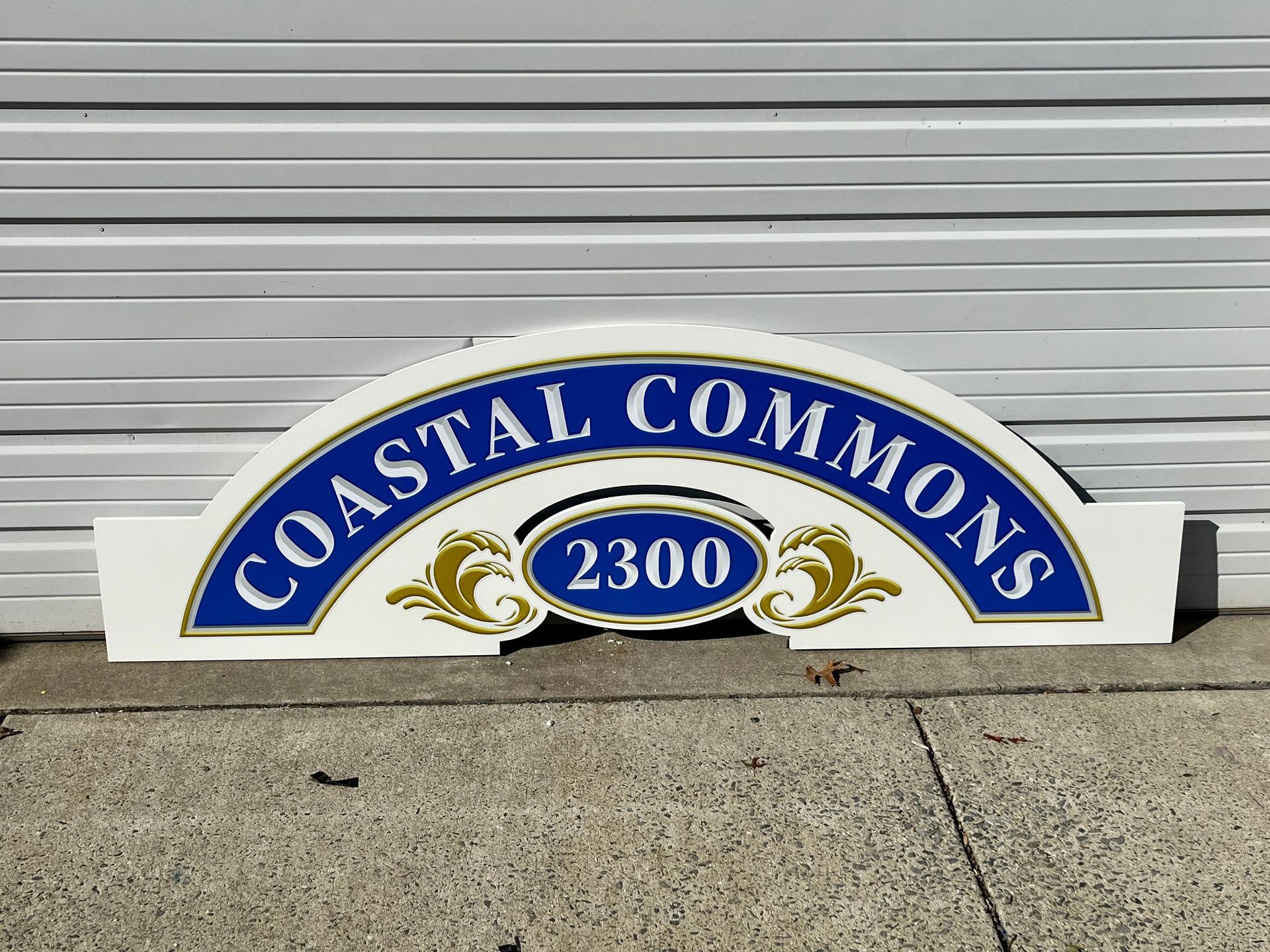 Coastal Commons sign in white, blue, and gold with address 