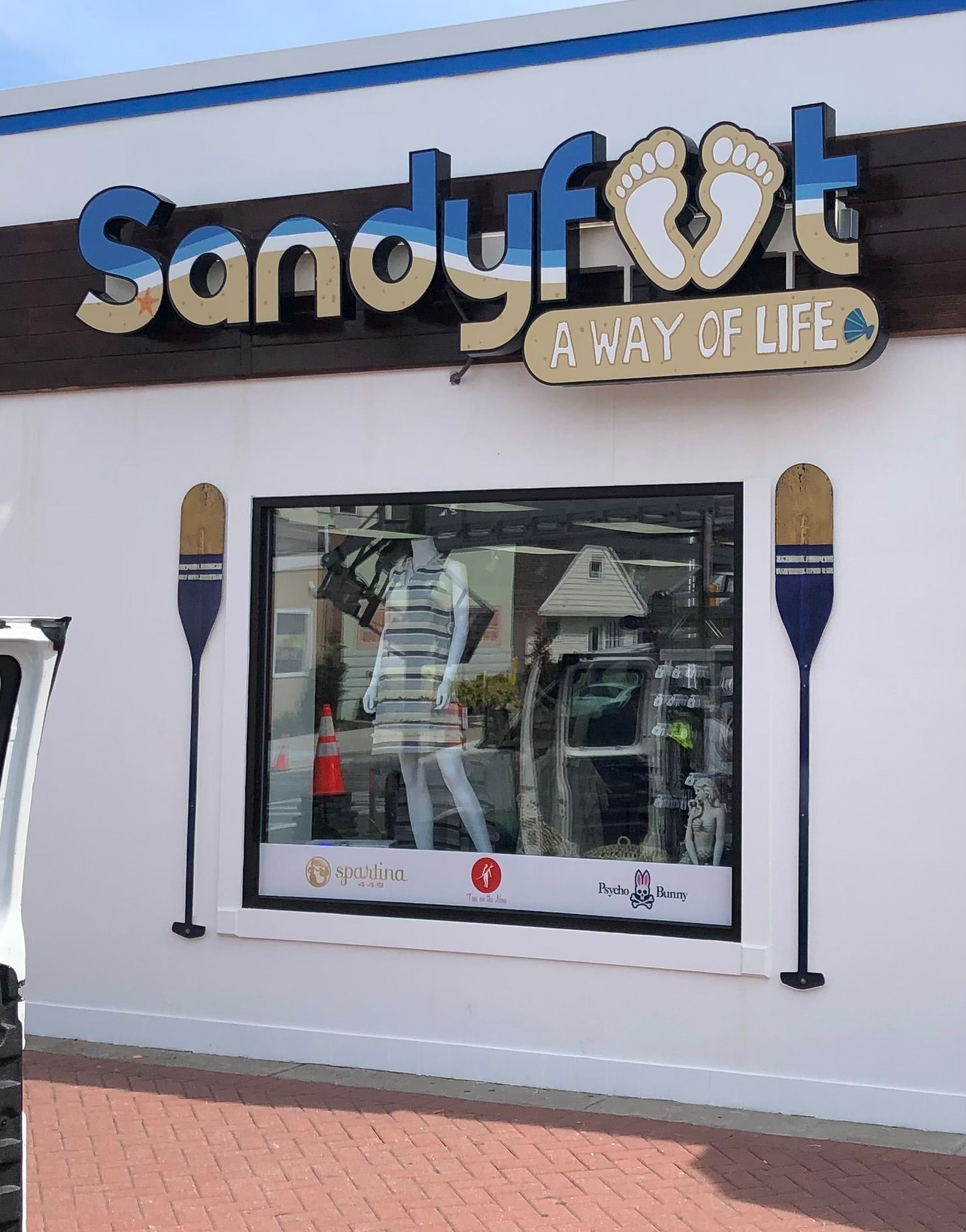 Sandyfoot store front with sign above window, featuring merchandise display and oar decorations.