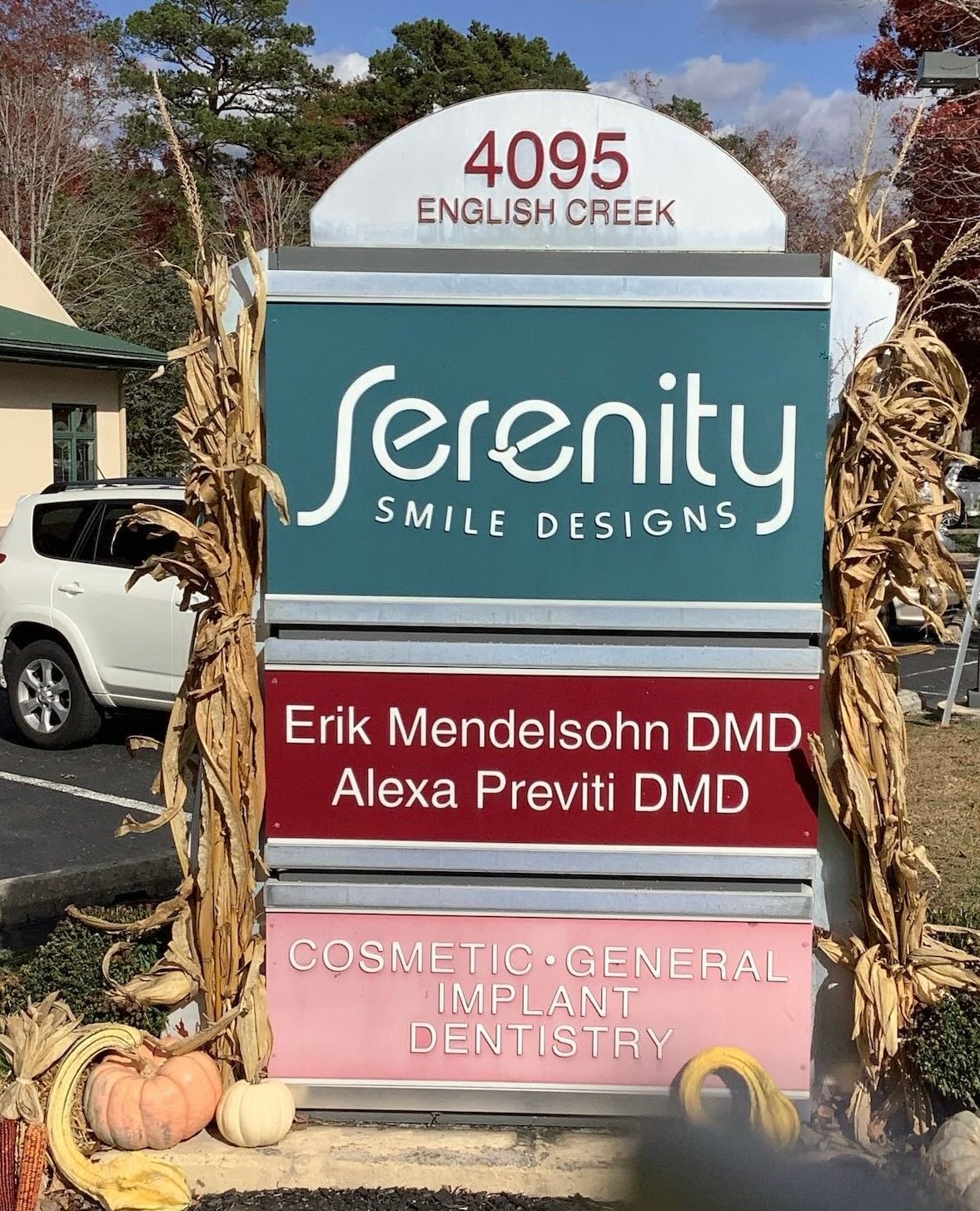 Sign for Serenity Smile Designs dental office at 4095 English Creek, featuring names and services.