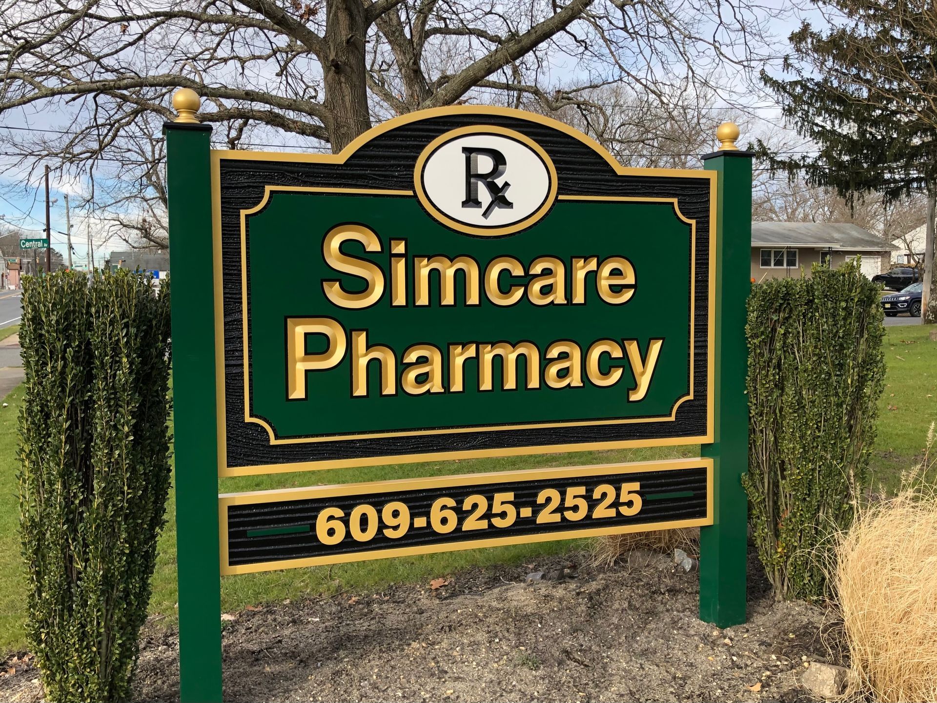 Sign for Simcare Pharmacy with green and gold trim; phone number is 609-625-2525.