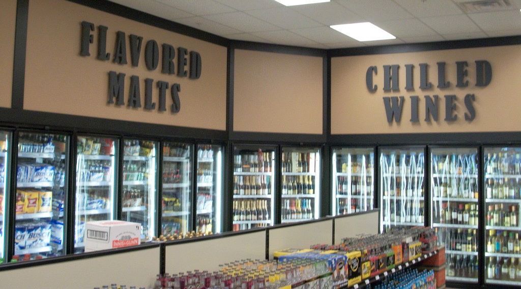 Inside a convenience store, refrigerators displaying drinks under signs for 