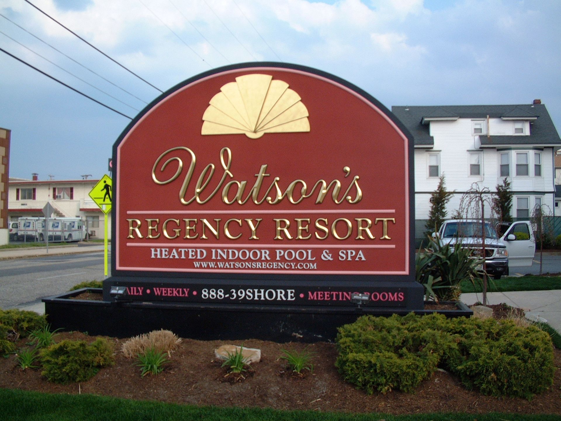 Sign for Watson's Regency Resort. Burgundy with gold lettering, fan design. Features a heated indoor pool and spa.