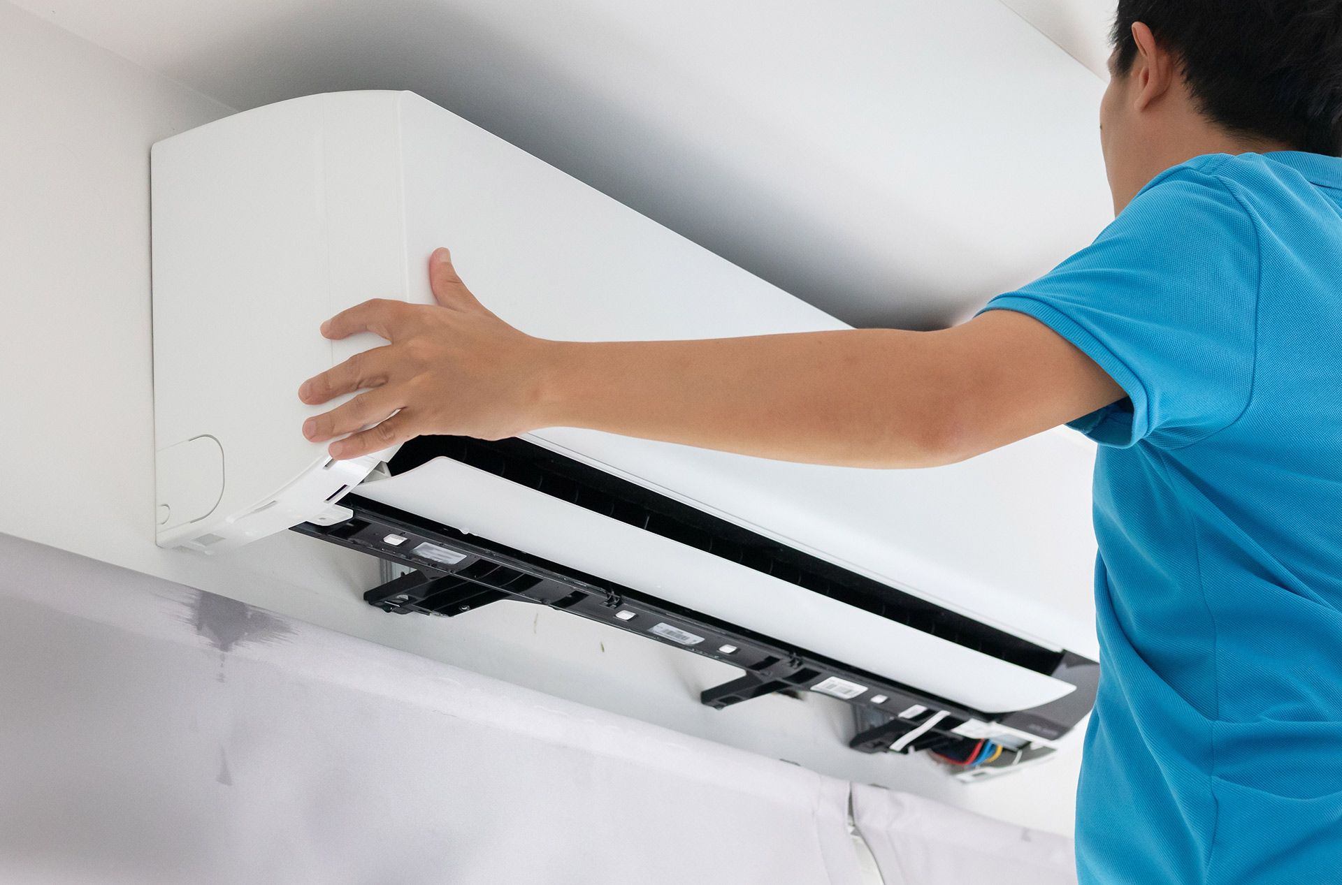 Technician cleaning a wall-mounted air conditioner indoors