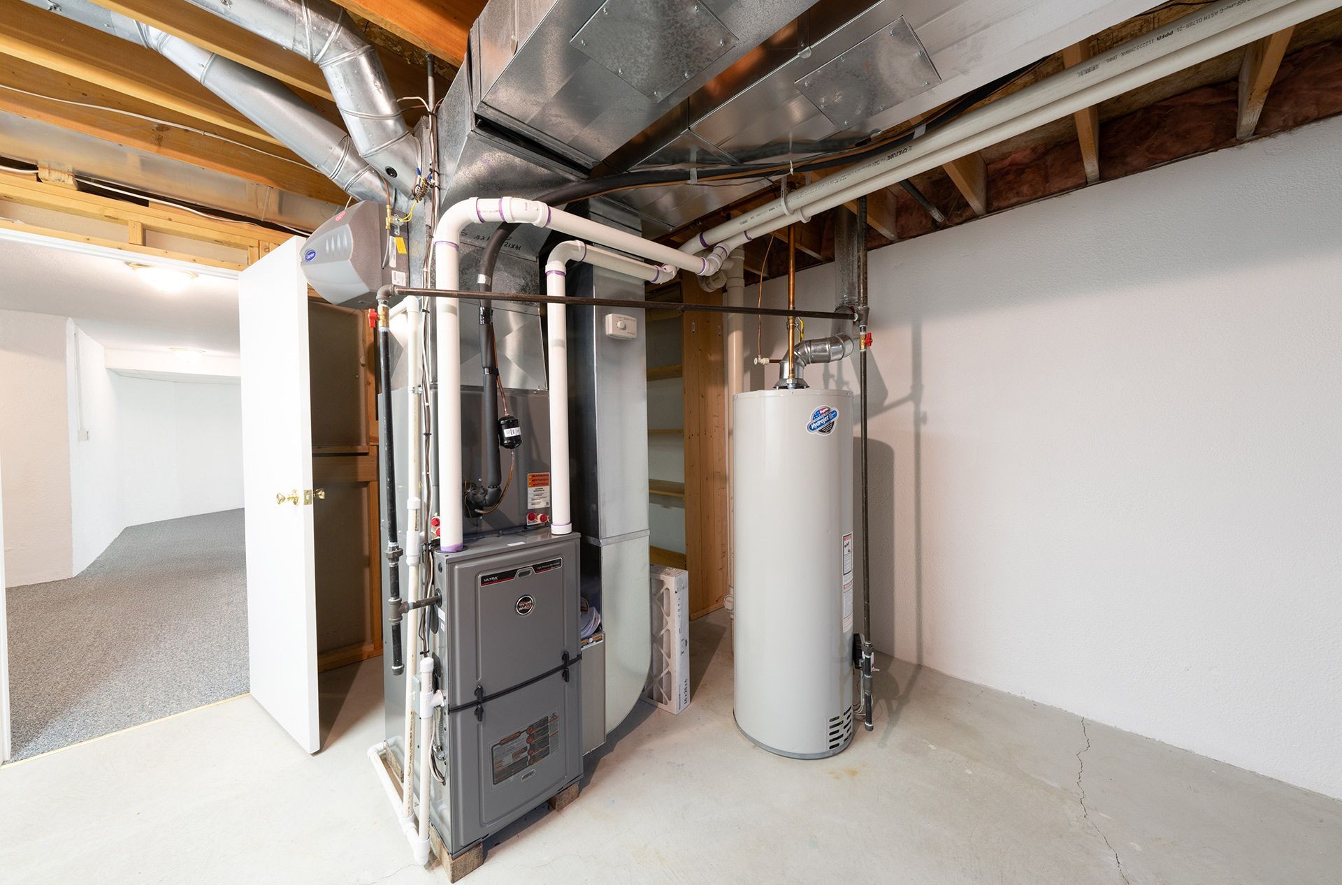 Basement utility room with furnace, water heater, exposed ducts, and unfinished walls