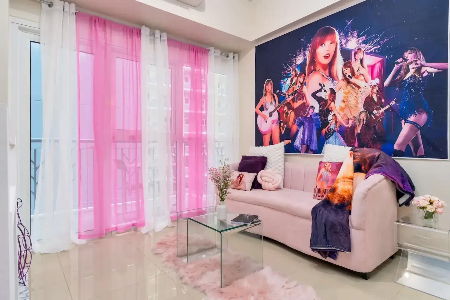 A living room with a pink couch , a glass coffee table , and a painting on the wall.