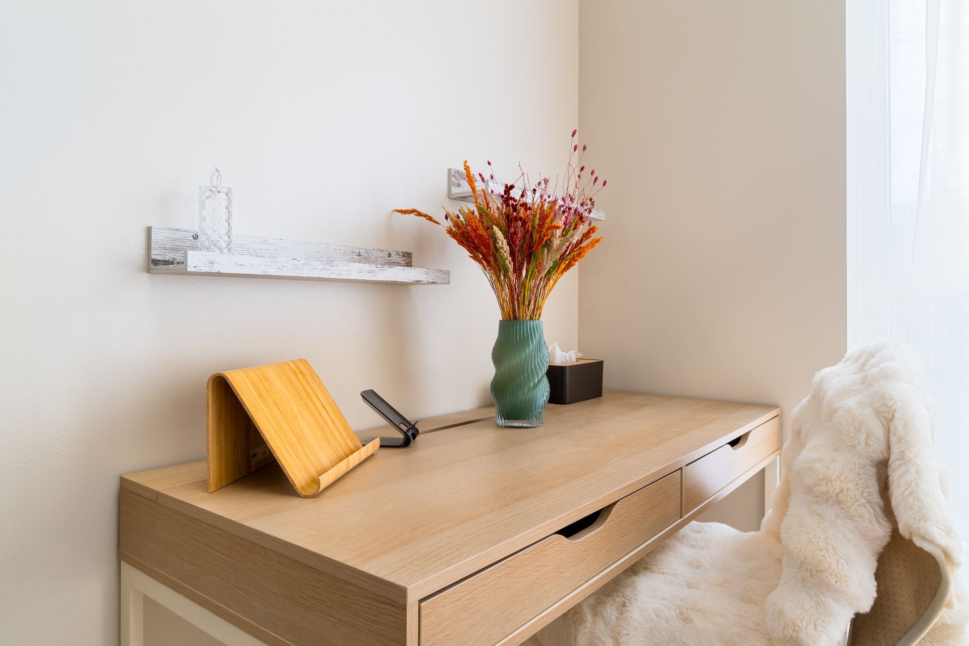 A wooden desk with a vase of flowers on it.