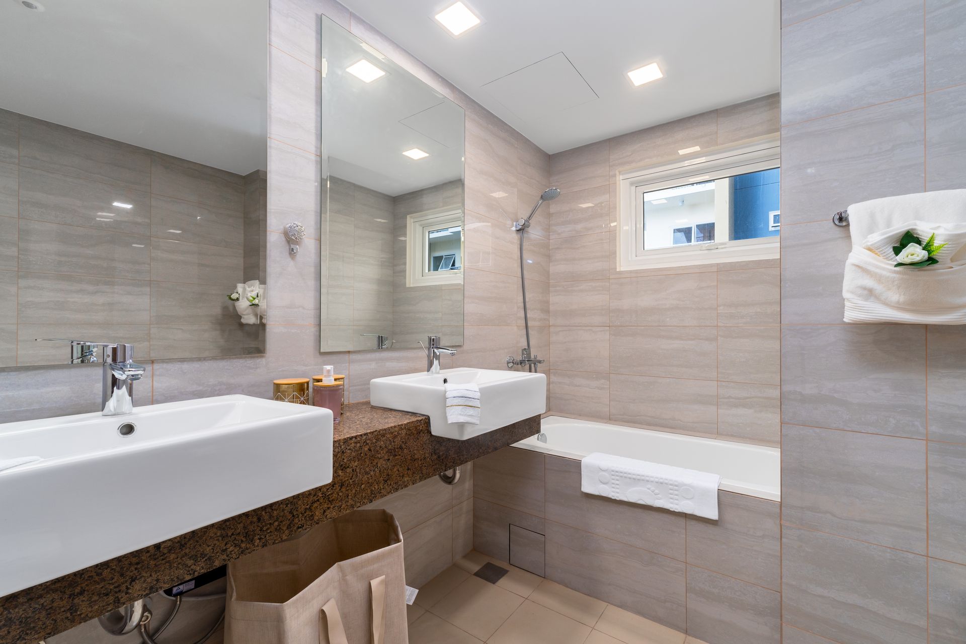 A bathroom with two sinks , a tub and a mirror.