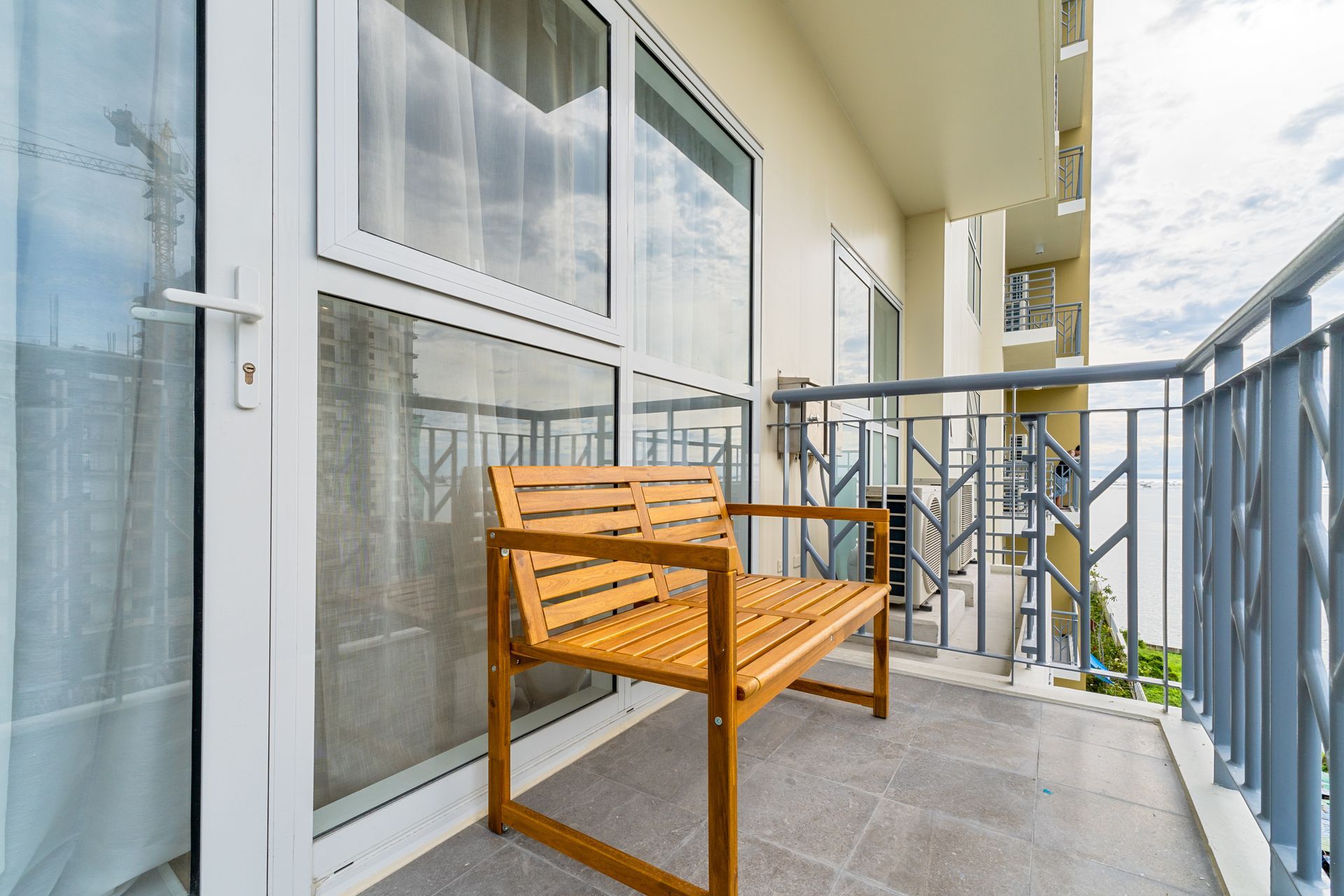 A wooden bench is sitting on a balcony next to a window.