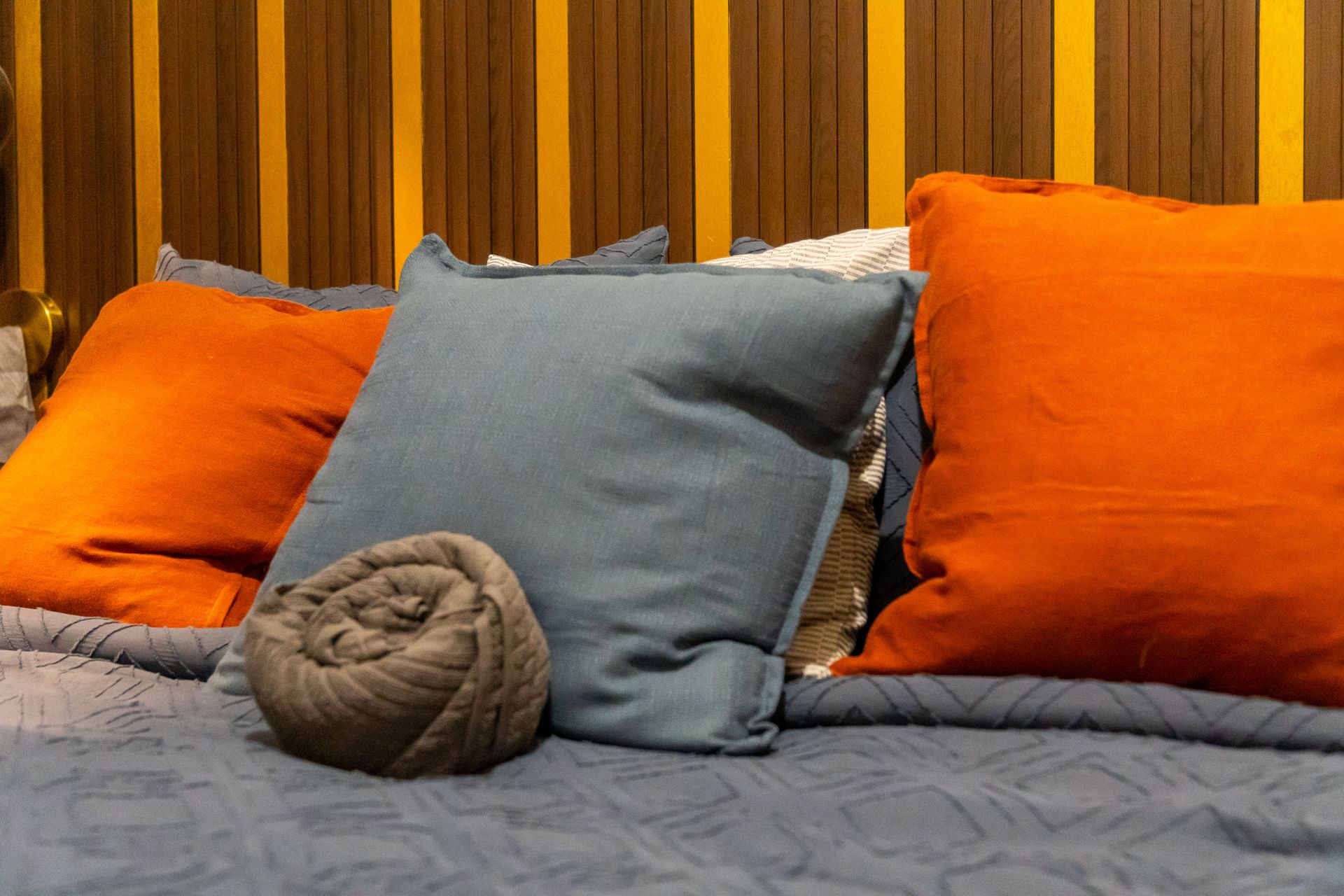 A bed with a bunch of pillows and a blanket on it.