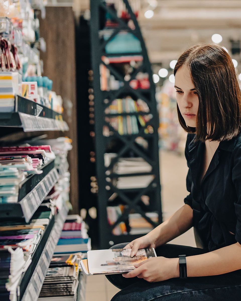 A woman is sitting in a store reading a book.