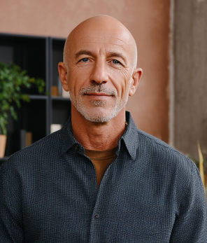 Bald, older man in blue shirt, looking at the camera.
