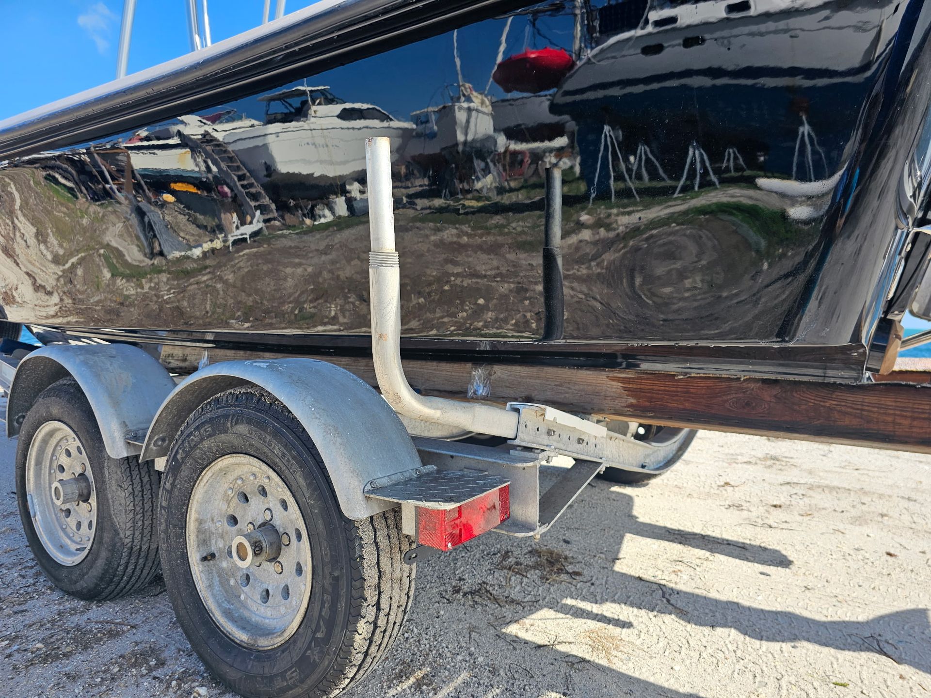 A boat is sitting on a trailer on the beach.