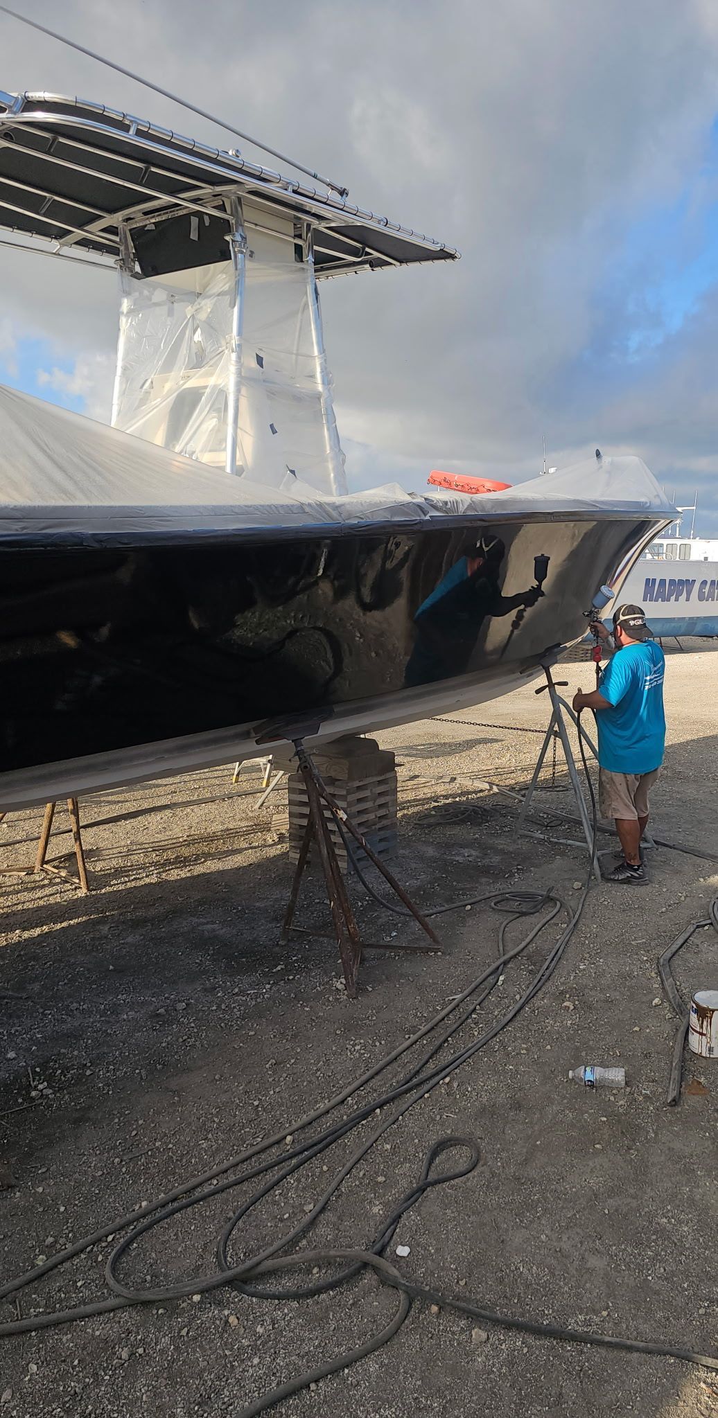 A man is standing next to a boat in a parking lot.