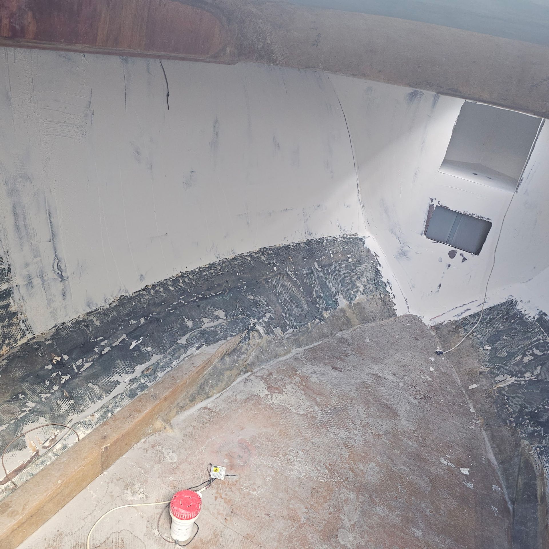 A dirty room with a red bottle on the floor