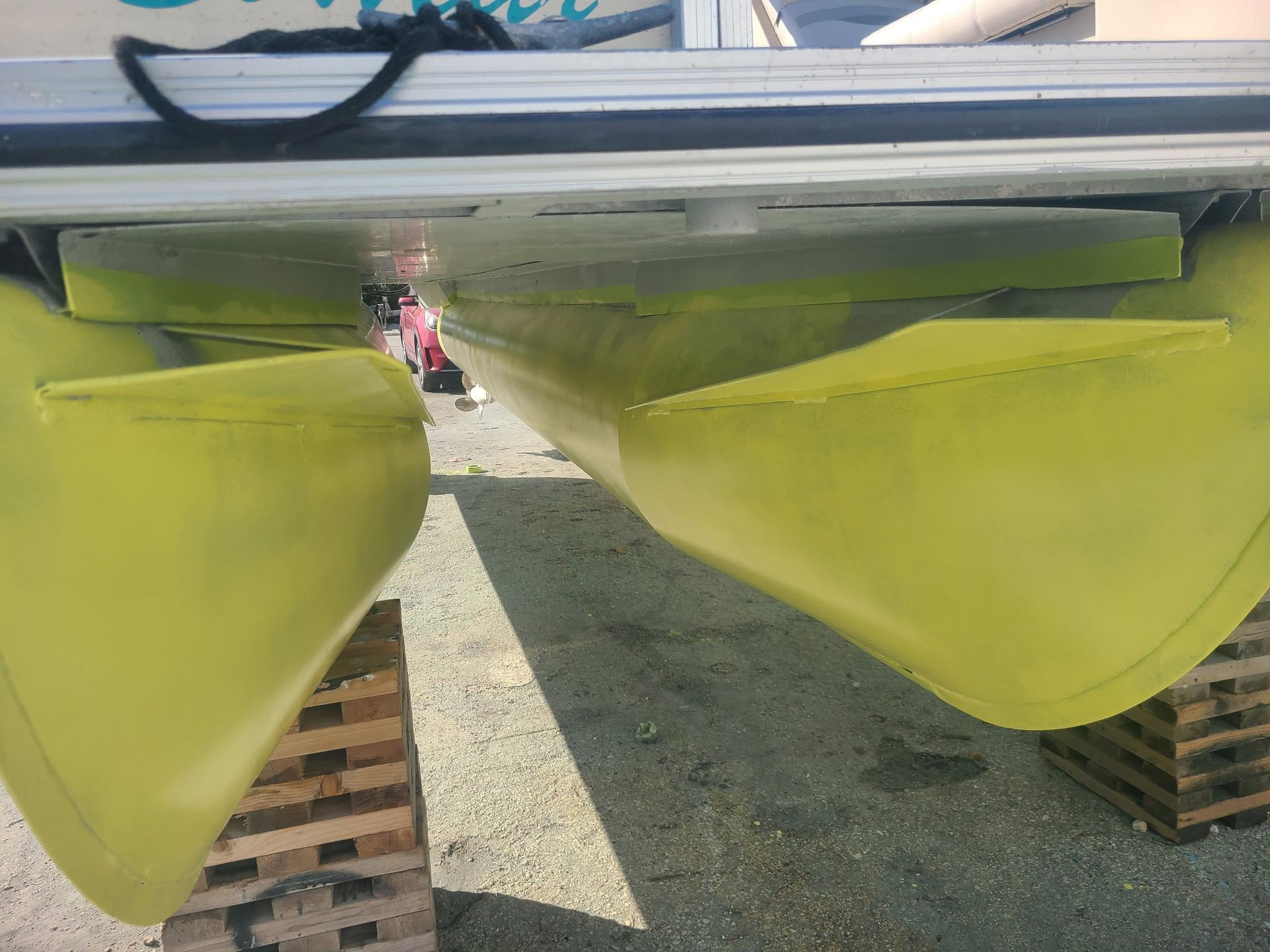 A yellow boat is sitting on wooden blocks on the ground